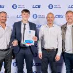 This photo depicts a student with their award against the LCBU photo wall.