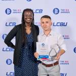 This photo depicts a student with their award against the LCBU photo wall.