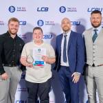 This photo depicts a student with their award against the LCBU photo wall.