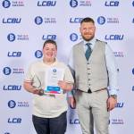 This photo depicts a student with their award against the LCBU photo wall.