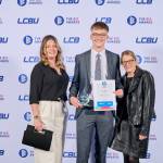 This photo depicts a student with their award against the LCBU photo wall.