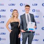 This photo depicts a student with their award against the LCBU photo wall.
