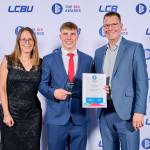 This photo depicts a student with their award against the LCBU photo wall.