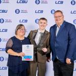 This photo depicts a student with their award against the LCBU photo wall.
