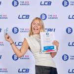 This photo depicts a student with their award against the LCBU photo wall.