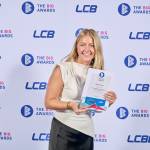 This photo depicts a student with their award against the LCBU photo wall.