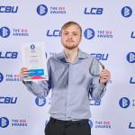 This photo depicts a student with their award against the LCBU photo wall.