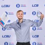 This photo depicts a student with their award against the LCBU photo wall.