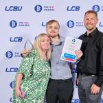 This photo depicts a student with their award against the LCBU photo wall.