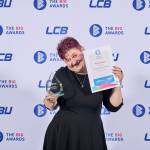 This photo depicts a student with their award against the LCBU photo wall.