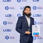This photo depicts a student with their award against the LCBU photo wall.