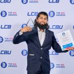 This photo depicts a student with their award against the LCBU photo wall.