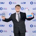 This photo depicts a student with their award against the LCBU photo wall.