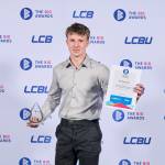 This photo depicts a student with their award against the LCBU photo wall.