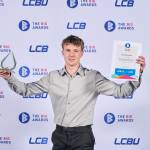 This photo depicts a student with their award against the LCBU photo wall.
