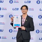 This photo depicts a student with their award against the LCBU photo wall.