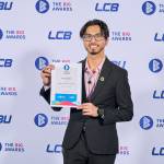 This photo depicts a student with their award against the LCBU photo wall.