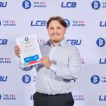 This photo depicts a student with their award against the LCBU photo wall.