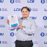 This photo depicts a student with their award against the LCBU photo wall.