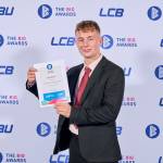 This photo depicts a student with their award against the LCBU photo wall.