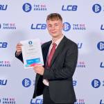 This photo depicts a student with their award against the LCBU photo wall.