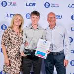 This photo depicts a student with their award against the LCBU photo wall.