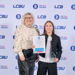 This photo depicts a student with their award against the LCBU photo wall.