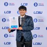 This photo depicts a student with their award against the LCBU photo wall.