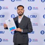 This photo depicts a student with their award against the LCBU photo wall.
