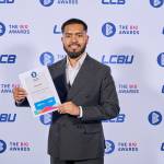 This photo depicts a student with their award against the LCBU photo wall.