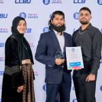 This photo depicts a student with their award against the LCBU photo wall.