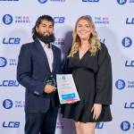 This photo depicts a student with their award against the LCBU photo wall.