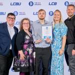 This photo depicts a student with their award against the LCBU photo wall.