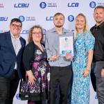 This photo depicts a student with their award against the LCBU photo wall.