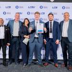 This photo depicts a student with their award against the LCBU photo wall.