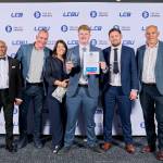 This photo depicts a student with their award against the LCBU photo wall.