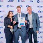 This photo depicts a student with their award against the LCBU photo wall.