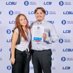 This photo depicts a student with their award against the LCBU photo wall.