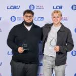 This photo depicts two students with their awards against the LCBU photo wall.