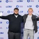 This photo depicts two students with their awards against the LCBU photo wall.