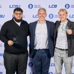This photo depicts two students with their awards against the LCBU photo wall.