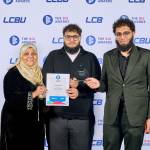 This photo depicts a student with their award against the LCBU photo wall.