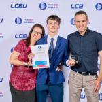 This photo depicts a student with their award against the LCBU photo wall.