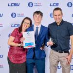 This photo depicts a student with their award against the LCBU photo wall.