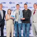 This photo depicts a student with their award against the LCBU photo wall.