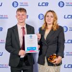 This photo depicts a student with their award against the LCBU photo wall.