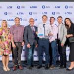 This photo depicts a student with their award against the LCBU photo wall.