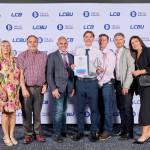 This photo depicts a student with their award against the LCBU photo wall.