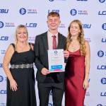This photo depicts a student with their award against the LCBU photo wall.