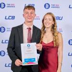 This photo depicts a student with their award against the LCBU photo wall.